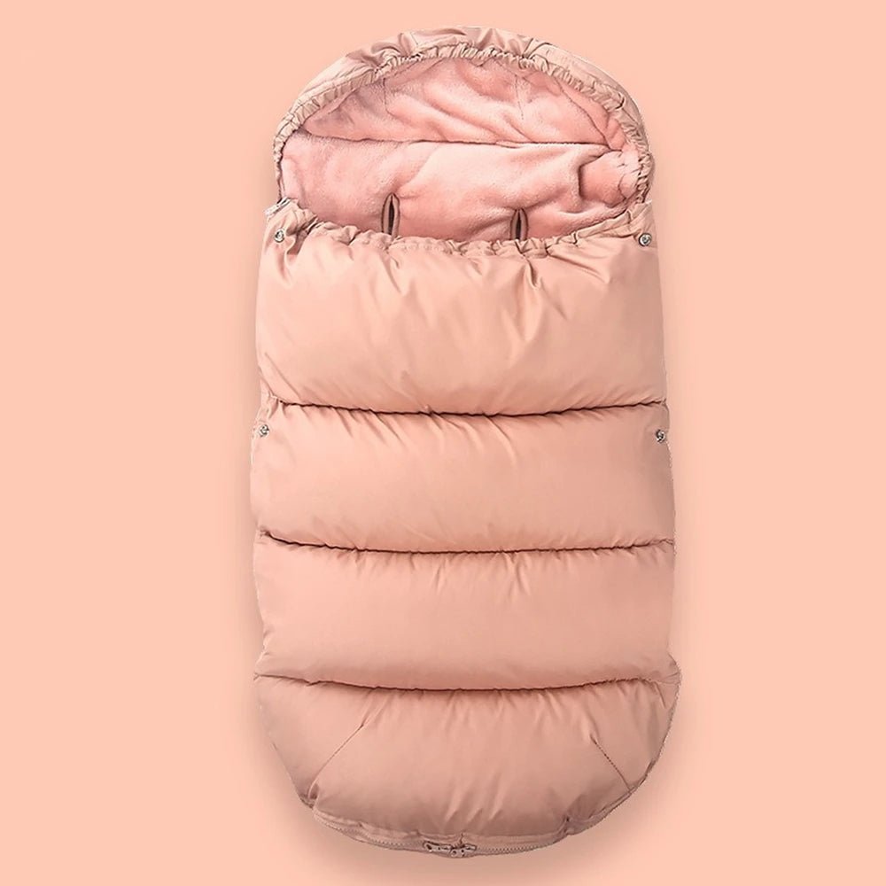La Chancelière Bébé est une gigoteuse rose matelassée avec capuche et doublure polaire douce, offrant une protection thermique idéale pour les poussettes et les sièges auto. Présentée sur un fond rose pastel assorti.