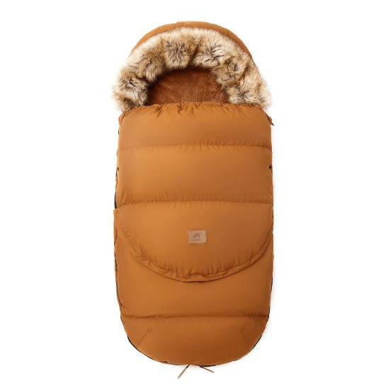 La Chancelière | 0-36 mois est une gigoteuse marron à capuche avec bordure en fausse fourrure, tissu doux et isolant pour le confort de bébé et une protection thermique, plus un petit patch rectangulaire sur le devant.