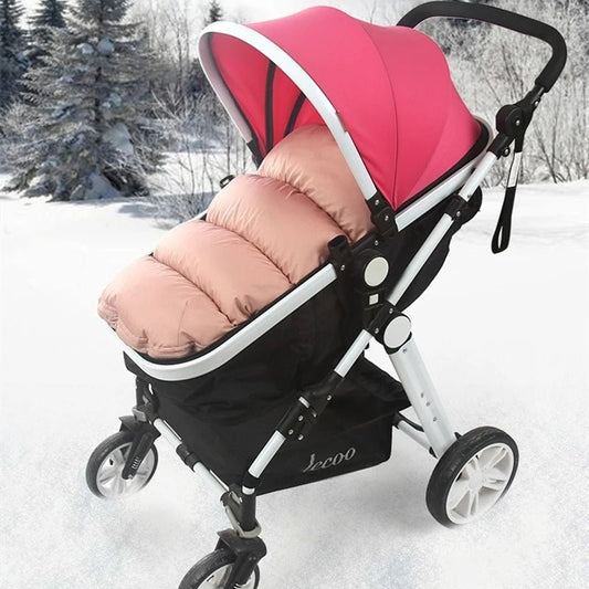 La chancelière Bébé, en rose et beige avec un auvent, offre une excellente protection thermique et est représentée garée sur la neige au milieu d'arbres hivernaux et d'un paysage hivernal paisible.