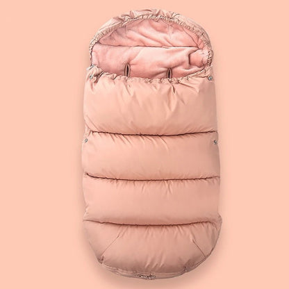 La Chancelière Bébé est une gigoteuse rose matelassée avec capuche et doublure polaire douce, offrant une protection thermique idéale pour les poussettes et les sièges auto. Présentée sur un fond rose pastel assorti.