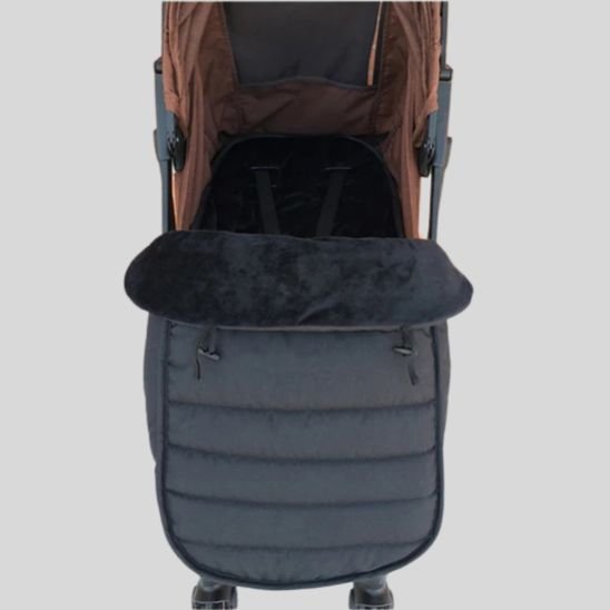 Gros plan d'une poussette noire et marron avec la chancelière bébé WarmCott™ fixée pour la protéger pendant l'hiver, sur fond gris clair. La poussette vide est vue de dessus.