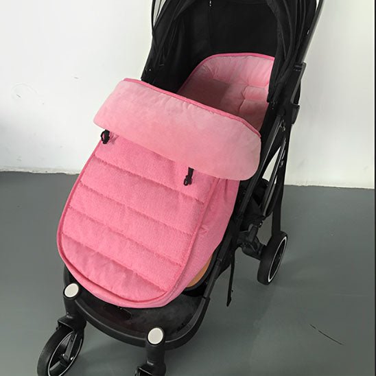 Une poussette noire avec une Chancelière pour Poussette rose en tissu Oxford imperméable pour la protection contre les intempéries, présentée à l'intérieur sur un sol gris et sur un fond de mur blanc.