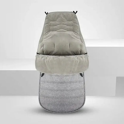 La Chancelière pour Poussette, présentée debout sur un fond clair uni, est confectionnée en tissu imperméable Oxford matelassé gris et offre douceur, isolation et protection fiable contre les intempéries à votre poussette.