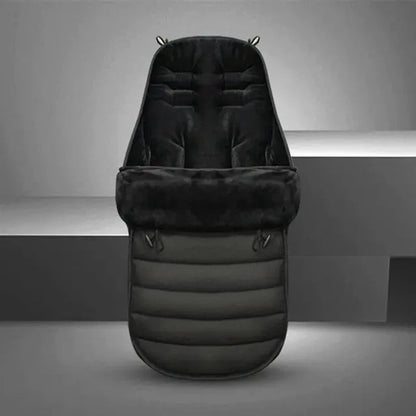La Chancelière pour Poussette, présentée debout sur un fond gris minimaliste, présente un design rembourré noir avec une texture matelassée douce pour offrir protection contre les intempéries et confort à votre bébé.