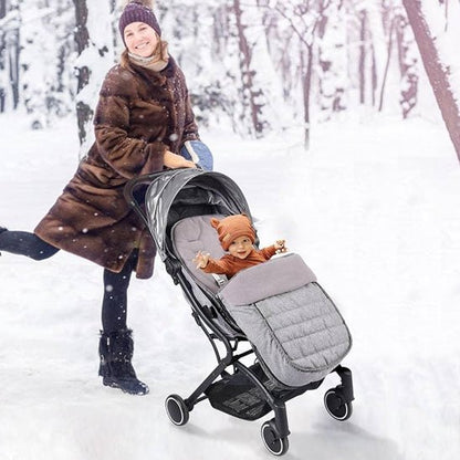 Une femme vêtue d'un manteau de fourrure marron pousse une poussette équipée de la Chancelière pour Poussette, gardant son bébé au chaud et protégé de la forêt enneigée grâce à son tissu Oxford imperméable et à son excellente protection contre les intempéries.