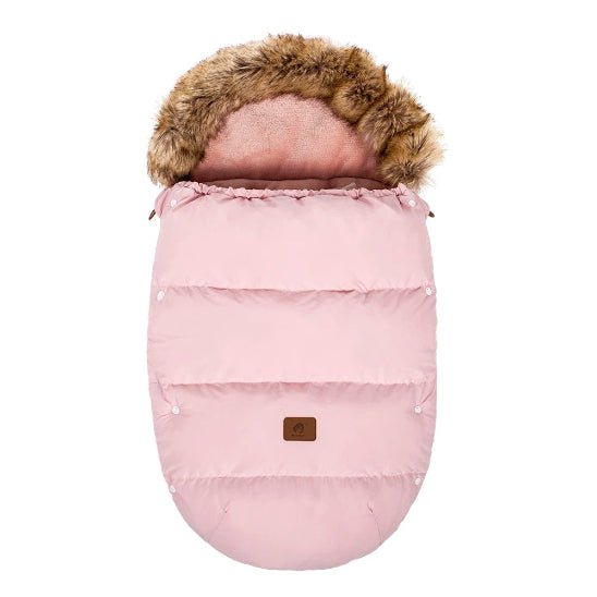 La Chancelière Poussette | 0-24 mois est une chancelière de poussette rose de forme ovale avec des coutures matelassées et une capuche bordée de fausse fourrure pour la protection thermique, ainsi qu'un petit patch marron sur le devant pour le confort de bébé, présentée sur un fond blanc.