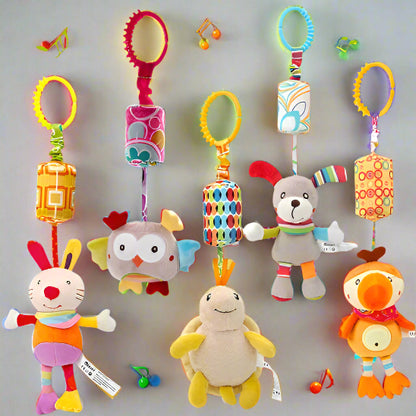 Cinq jouets Jouet - Hochet Bébé colorés avec des anneaux en plastique sont suspendus en rangée. Chaque personnage en peluche présente des motifs brillants et des textures douces pour l'éveil sensoriel. De petites pièces de jouets sont éparpillées à proximité.