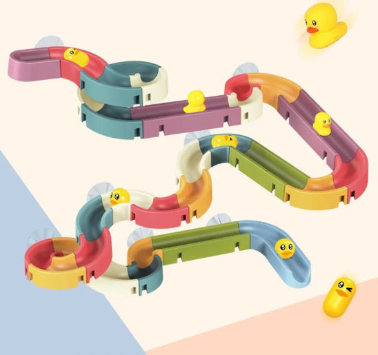 Le Jouet de bain - piste de course est une piste de jeu en plastique coloré avec de multiples rebondissements, mettant en vedette de petites figurines jaunes en forme de canard et de capsule avec des visages le long de la piste et sur le sol en arrière-plan.