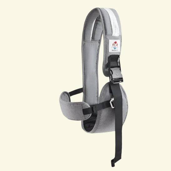 Le Porte Bébé - HandsFree est un harnais d'épaule rembourré gris avec une bande blanche, des sangles réglables noires et une boucle à dégagement latéral - une solution mains libres idéale pour les parents actifs, présentée sur un fond blanc cassé.