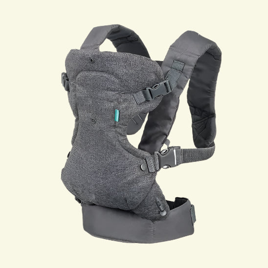 Le Porte Bebe physio | FlipAdvanced™ en gris foncé est doté de bretelles rembourrées, de boucles réglables et d'une large ceinture pour un confort polyvalent, présenté sur un fond blanc cassé.