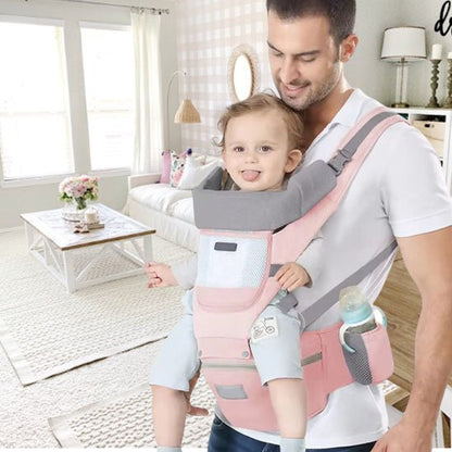 Un homme sourit à un bébé assis dans le Porte Bebe | WaistStool™ rose et gris, tenant une cuillère tandis qu'un biberon se trouve dans la poche latérale, offrant confort et sécurité pour les deux.