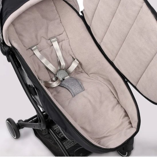 Gros plan de la Poussette Chancelière noire avec chancelière thermique beige et harnais cinq points, présentée ouverte et vide sur fond clair, présentant une compatibilité universelle.