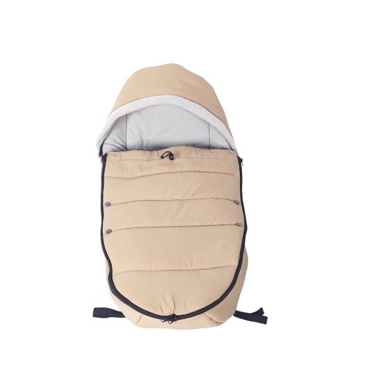 La Poussette Chancelière est une gigoteuse beige à capuche et fermeture éclair noire, présentée à plat sur fond blanc. Son rembourrage offre une protection thermique et ses sangles inférieures réglables garantissent une compatibilité universelle avec la plupart des poussettes.