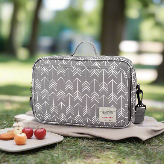 Le Sac à langer bébé | Poussette est un sac à langer rectangulaire gris orné d'un motif de flèches blanches, doté d'une poignée sur le dessus, d'une bandoulière amovible et d'une étiquette « aboutbaby » sur le devant, idéal pour les sorties. Présenté sur fond blanc.