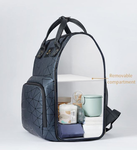 Le Sac à Langer dos, de couleur gris foncé avec coutures géométriques et poignées sur le dessus, est idéal pour les sorties en famille. Il est doté d'un côté ouvert révélant un compartiment amovible contenant des articles comme une tasse, une peluche, des couches et des vêtements. Parfait pour les parents modernes.