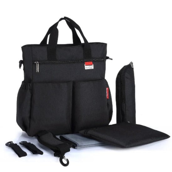 Le Sac à Langer - Fourre-tout noir, conçu pour les parents modernes avec des anses courtes et de multiples poches, est présenté avec un porte-bouteille assorti, un matelas à langer, une pochette et deux sangles sur fond blanc.