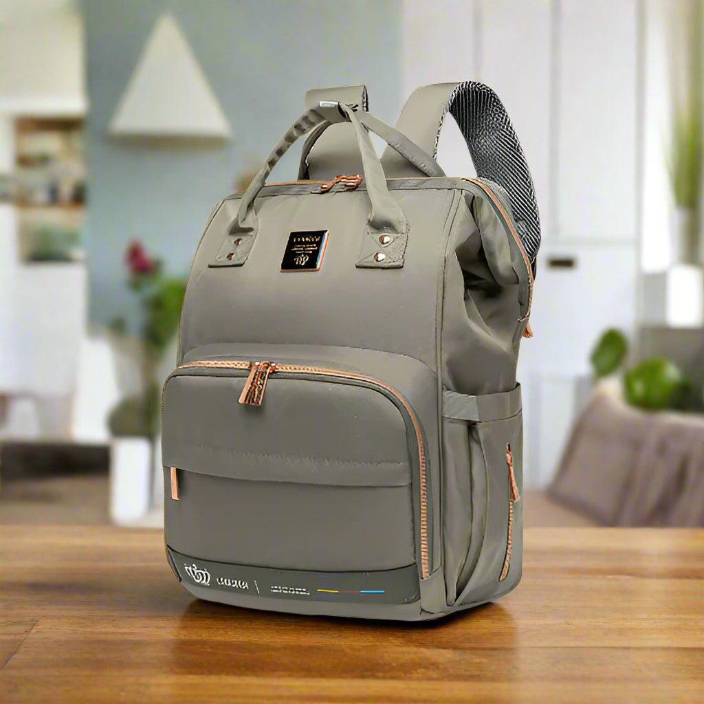 Un Sac à langer - LeQueen Bag pour Bébé gris avec des fermetures éclair et des poignées marron est posé sur une table en bois dans un salon moderne - idéal pour les parents organisés en déplacement.