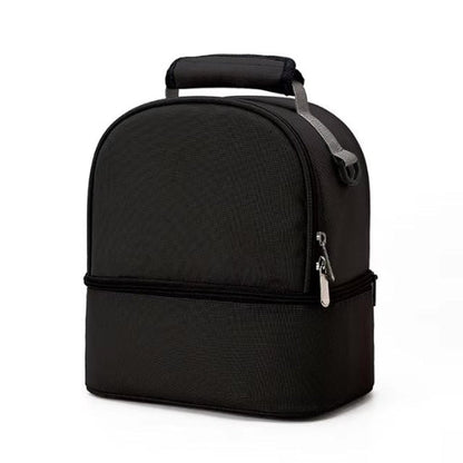Le Sac Bébé - Petit est un sac à lunch noir rectangulaire aux bords arrondis, doté d'une poignée sur le dessus et de deux compartiments pour une organisation facile. Sa performance thermique préserve la fraîcheur des aliments, présenté debout sur un fond blanc uni.