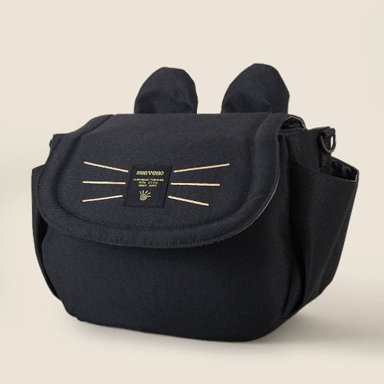 Le Sac bébé Poussette est un sac à langer noir avec des détails rappelant ceux dun chat, notamment des protubérances en forme doreilles et des coutures en forme de moustaches sur le rabat avant. Il est doté de poches latérales et dune étiquette Sunveno, ce qui en fait un accessoire pratique pour les parents en déplacement.