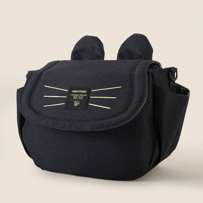 Le Sac bébé Poussette est un sac à langer noir avec des détails rappelant ceux dun chat, notamment des protubérances en forme doreilles et des coutures en forme de moustaches sur le rabat avant. Il est doté de poches latérales et dune étiquette Sunveno, ce qui en fait un accessoire pratique pour les parents en déplacement.
