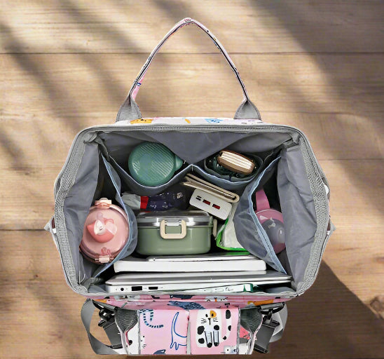 Le Sac pour Bébé | Chat, un sac à dos aux couleurs pastel, est doté d'un système d'organisation intelligent avec des compartiments abritant une boîte à bento verte, une bouteille d'eau rose et des petits contenants. Orné d'illustrations de chats, il est à la fois pratique et charmant.