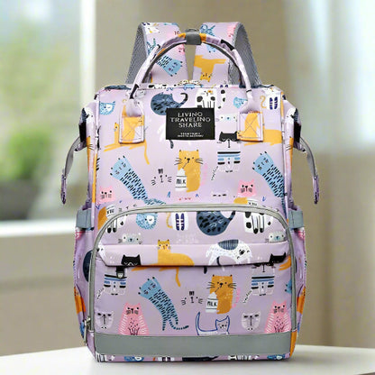 Le Sac pour Bébé | Chat est un sac à dos polyvalent et coloré orné d'un motif ludique de chats de dessin animé sur un fond rose clair. Doté de multiples poches et d'un système d'organisation intelligent, il est parfait pour un usage quotidien, les voyages et le partage.